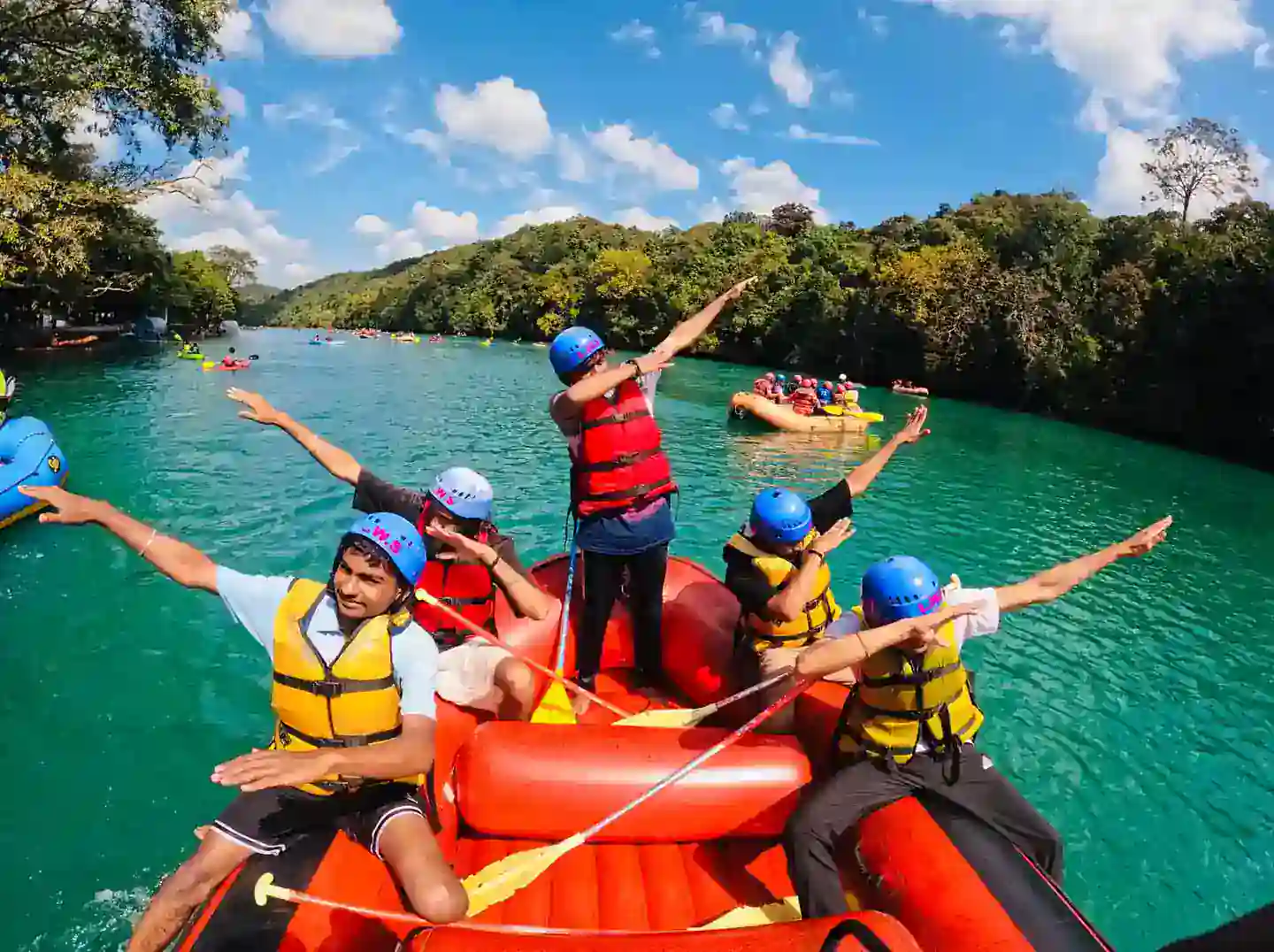 Men's rafting group celebrating on turquoise Kali River in Dandeli