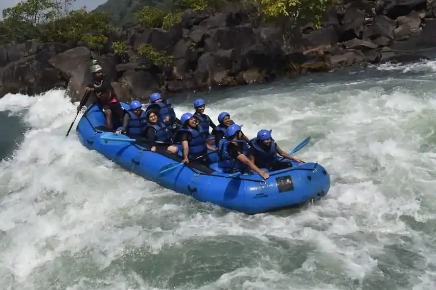 Women's rafting group with paddles raised on emerald Kali River in Dandeli