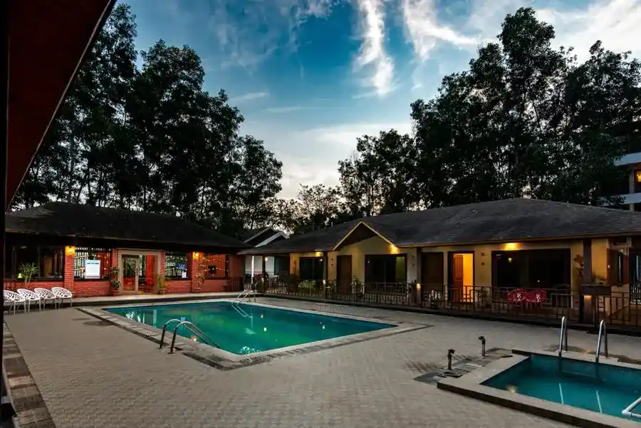 Large swimming pool surrounded by forest at Dew Drops Jungle Resort