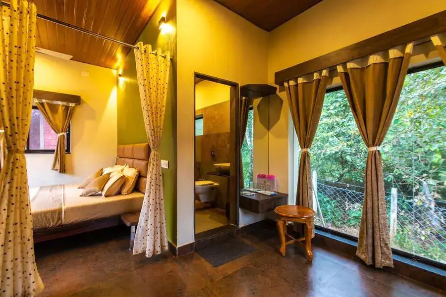 AC Deluxe room with large window overlooking dense forest at Tusker Trails